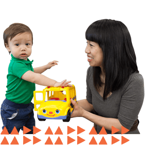 A mom and young son playing with a toy bus at the Chicago Public Library.