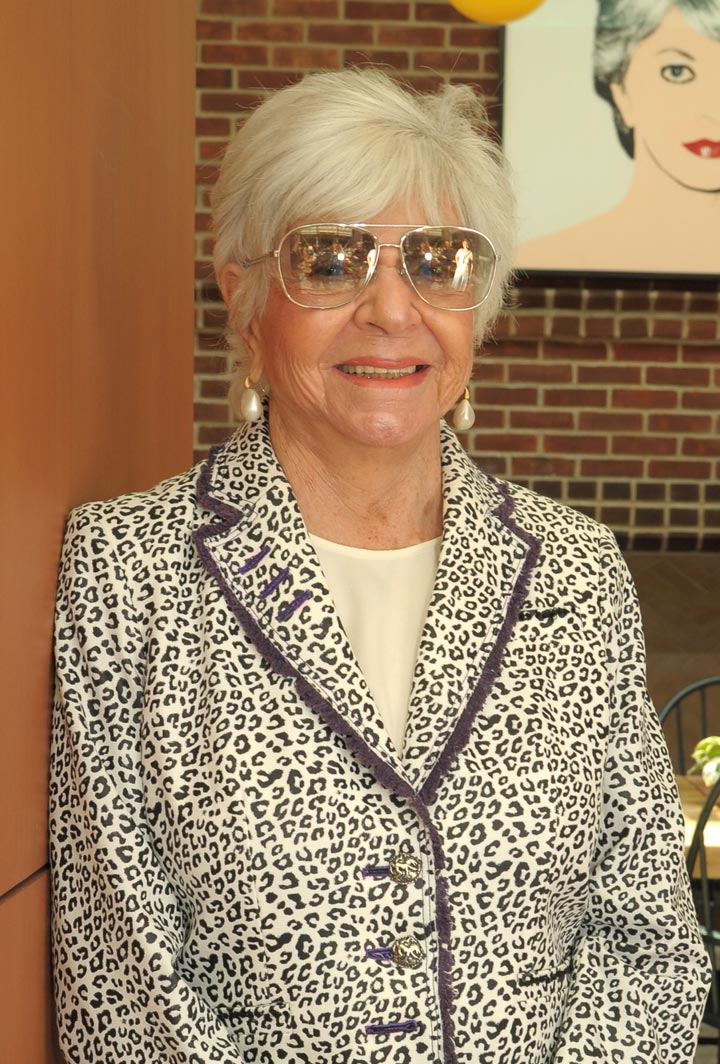 Cindy Pritzker smiling with a Warhol painting behind her.